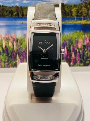 Skagen svart klocka med diamanter - Stilren klocka från Skagen med svart rektangulär urtavla, silverfärgat hölje och diskreta diamanter på urtavlan. Klockan har ett svart band och detaljer i silver, samt dekorativa stenar på boetten. Perfekt för dig som gillar minimalistisk design.Nytt batteri, slitet men funktionellt armband, säljes i befintligt skick enligt bilderna!