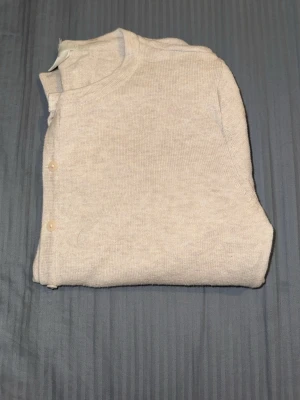 Beige kofta från H&M BASIC, S - Mysig beige kofta från H&M BASIC i storlek S. Koftan har rund halsringning, knappar framtill och är stickad i ett mjukt material. Perfekt att slänga på sig när det är lite kyligt ute.