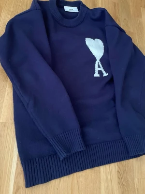 Mörkblå stickad tröja från Ami - Snygg mörkblå stickad tröja från ami Paris. Passar bäst till lite kallare dagar eller kvällar. Modellen är 166cm lång. Perfekt för en stilren och trendig look. Diskuterar gärna pris🙂