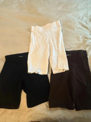 3-pack cykelshorts i svart, vitt och brunt - Säljer ett 3-pack cykelshorts i svart, vitt och brunt. Alla har hög midja och är tillverkade i stretchigt bomullsmaterial. Perfekta för sommaren och passar till många olika outfits. Den svarta är använd medans dem andra knappt e använda!