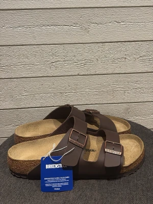 Bruna Birkenstock  - Bruna Birkenatock tofflor i storlek 45, tofflorna är aldrig använda bara testade hemma men säljs pga förstora 