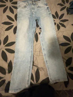 Ljusblå raka jeans från BZB - Säljer ett par ljusblå jeans från BZB med rak passform och klassisk femficksdesign. Jeansen har en snygg tvättad look och är tillverkade i denim. Perfekta för dig som gillar en avslappnad och trendig stil.