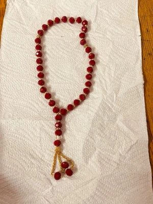 Rött misabaha med pärlor och gulddetaljer  - Unikt misabaha med facetterade röda pärlor och små guldfärgade detaljer mellan varje pärla. 