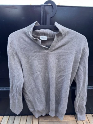Grå stickad tröja från John Henric🙌🤩 - Snygg grå stickad tröja från John Henric med krage och v-ringad öppning. Tröjan har långa ärmar och ribbade muddar vid ärmslut och nederkant. Perfekt för dig som gillar stilrena och klassiska plagg.🙌🤩