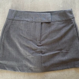 Grå kort kjol - Stilren grå kort kjol från New Yorker. Kjolen är aldrig använd och har prislappen kvar. Den är midwaist men går att vika ner till low waist om man vill, den har inbyggda shorts och är i storlek s.❤️