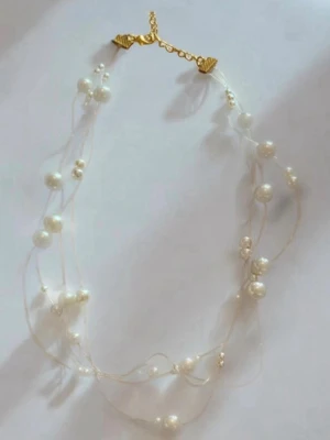 Transparant halsband med vita pärlor - Snyggt halsband med tunna genomskinliga trådar och vita pärlor i olika storlekar. Halsbandet har ett guldfärgat spänne och ger en elegant och trendig look. Perfekt för dig som gillar stilrena accessoarer med en twist.