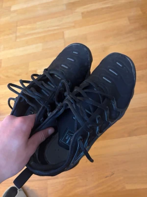 Svarta Nike Air Vapormax sneakers - Säljer ett par helsvarta Nike Air Vapormax sneakers med cool, skorna är använda och har lite skador på olika ställe . Men skorna är i bra skick som går utmärkt att använda