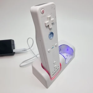 Laddstation 2 i 1 för Wii Remote + 2 batteripack - Laddstation för upp till två Wii-kontroller samtidigt. Inkluderar två uppladdningsbara batteripack som ersätter vanliga batterier.  • Laddar 2 kontroller samtidigt • 2 uppladdningsbara batteripack ingår • Förvaring och laddning i samma enhet • LED-indikator visar laddning  Specifikationer: Batterikapacitet: 2800 mAh Driftspänning: 5–12V Ström via original Wii-adapter Skyddskrets inbyggd Färg: Vit Storlek: 10,5 × 8,5 × 7 cm Vikt: 260 g  (Wii Remote på bilder ingår ej)
