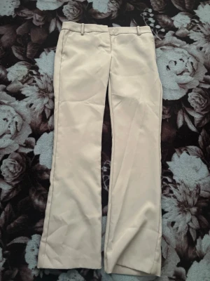 Beiga chinos med raka ben - Snygga beiga chinos med klassisk rak passform och bälteshällor i midjan. Byxorna har diskreta fickor fram och är tillverkade i ett mjukt bomullsmaterial som känns bekvämt hela dagen. Perfekta för en clean och stilren look. Pris kan diskuteras kom privat för fler bilder eller mer info!