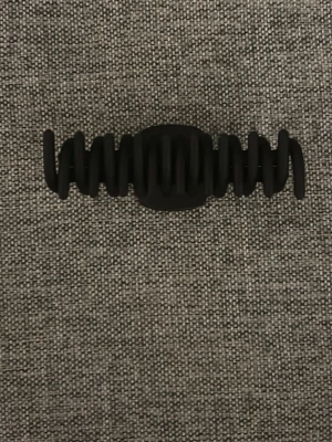 Svart hårklämma i matt plast - En stilren svart hårklämma i matt plast med vågig design. Perfekt för att snabbt sätta upp håret och hålla det på plats. Klämman har en modern look och passar till många olika frisyrer.