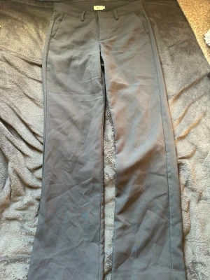 Gråa kostymbyxor från Nelly - Snygga gråa kostymbyxor från Nelly med raka ben och klassisk passform. Byxorna har hällor för skärp, sidofickor och stängs med dragkedja och hake. Perfekta för en stilren och trendig look.💗