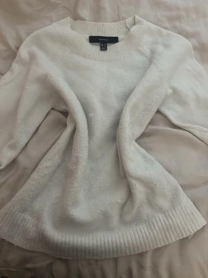 Vit stickad tröja från Vero Moda - Mysig vit stickad tröja från Vero Moda med rund halsringning och ribbade muddar vid ärmslut och nederkant. Tröjan har en enkel och stilren design som passar perfekt till många olika outfits. Materialet känns mjukt och bekvämt.