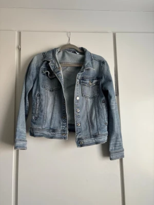 Ljusblå klassisk jeansjacka - Snygg ljusblå jeansjacka med klassisk passform och silverfärgade knappar. Jackan har två bröstfickor med lock och knappar samt två sidofickor. Tidlös modell som passar till det mesta och har coola slitningar för en avslappnad look. Pris kan diskuteras❤️