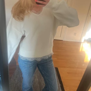 Vit stickad tröja med spetsdetalj - Mysig vit stickad tröja med v-ringning och fina spetsdetaljer vid halsringningen och nederkanten som är insydda. Tröjan är i storlek xxs men skulle säga att den mer är som en xs oxå eftersom den är ganska stor☺️☺️