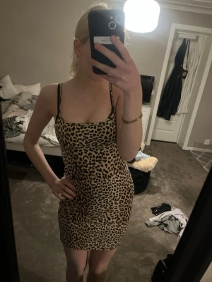 Leopardmönstrad kort klänning - Säljer en snygg leopardmönstrad kort klänning med tunna axelband. Klänningen har en figurnära passform och är perfekt för dig som vill sticka ut. Materialet känns mjukt och följsamt, troligen polyester. Inga synliga detaljer som dragkedja eller knappar.
