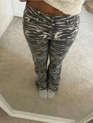 zebra jeans från Guess - Säljer ett par gråa jeans från Guess med vitt zebramönster. Jeansen har raka ben, normal midja och klassiska fem fickor. Snygg logga på bakfickan och coolt mönster som sticker ut. 