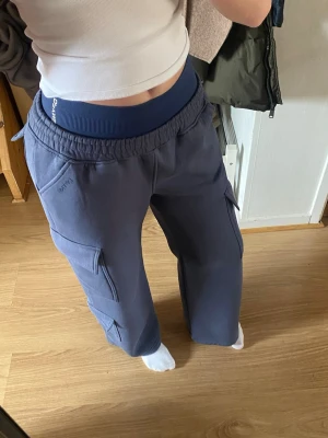 Cargobyxor från Dfyne - Säljer ett par blå cargobyxor från Dfyne med resår och knyt i midjan och flera stora fickor. Byxorna är mjuka o bekväma o har en så snygg passform! De är i nyskick utan några defekter. Pris kan diskuteras 🤗 