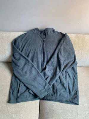 Mörkgrå fleecejacka med dragkedja - Mjuk och skön mörkgrå fleecejacka med dragkedja framtill. Perfekt för lager-på-lager och har en enkel, stilren design utan synliga loggor. Långärmad och tillverkad i fleece som håller dig varm under kyliga dagar.