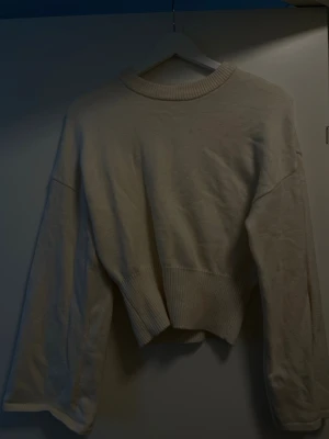 Beige croppad stickad tröja - Trendig beige stickad tröja med croppad passform och bred ribbad mudd i midjan. 