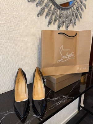 Louboutin klackar - Säljer ett par ikoniska svarta pumps från Christian Louboutin i glansigt lackläder med klassisk spetsig tå och den välkända röda sulan. Perfekta för dig som vill ha en elegant och tidlös sko med lyxig känsla.