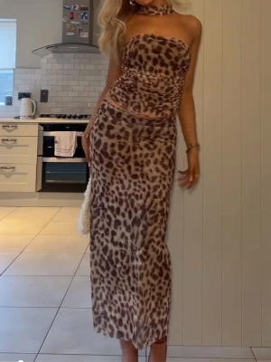 Leopardmönstrat set ( kjol, topp) från Zara - Trendig kjol och bandue topp leopardmönster i beige och bruna toner. Från Zara.  Tröjan är axelbandslös med figurnära passform och har en snygg scarf / band man knyter runt nacken . Perfekt för dig som vill sticka ut med en djurisk look. Säljer som ett set . Slutsåld , använd 1 gång.