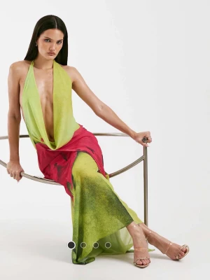 Grön och röd långklänning med djup urringning - Snygg långklänning med halterneck och djup urringning framtill. Klänningen har en öppen rygg och ett färgstarkt blommigt mönster i grönt, rött och svart. Otrolig klänning men säljer för att den är för tight över rumpan! Helt oanvänd, nypris 1500kr