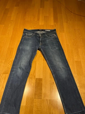 Replay Groover Selvage - Snygga mörkblå jeans från Replay med klassisk femficksdesign och raka ben. Jeansen har diskreta slitningar framtill och bakfickor med dekorativa sömmar. Märkespatch i läder baktill i midjan. Perfekta för en avslappnad och trendig stil.