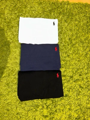 3-pack t-shirts från Ralph Lauren - Säljer tre klassiska t-shirts från Ralph Lauren i färgerna vit, marinblå och svart. Alla har korta ärmar och den ikoniska broderade loggan på bröstet. Perfekta basplagg till garderoben och tillverkade i mjuk bomull. Alla tre i storlek L. Helt nya