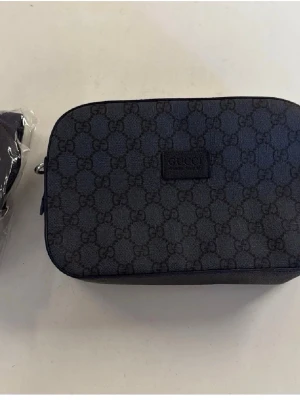 Mörkblå GG canvas handväska Gucci - Snygg mörkblå handväska från Gucci i klassisk GG canvas med monogrammönster över hela väskan. Rektangulär form och diskret läderpatch med logga framtill. Perfekt för dig som gillar stilrena designer och italiensk lyx.