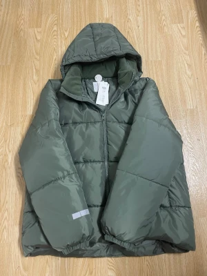 Grön pufferjacka med huva - Ny jacka ifrån Lindex med prislapp.Jackan är helt ny och aldrig använd.