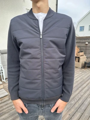 Mörkgrå cardigan - Snygg mörkgrå cardiganjacka från Massimo dutti. Jackan har dragkedja framtill, ribbade muddar och en stilren, sportig look. Perfekt för lager-på-lager och passar till jeans eller chinos.