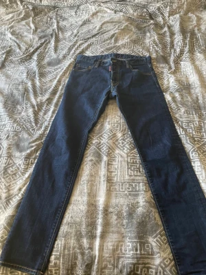 Mörkblå Dsquared2 jeans  - Snygga mörkblå skinny jeans från Dsquared2 med klassisk femficksmodell och tydlig logga på bakfickan. Jeansen har smal passform och är tillverkade i stretchigt denimtyg för extra komfort. Perfekta för en trendig och avslappnad stil.