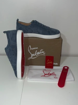 Blåa Christian Louboutin sneakers - Snygga blåa sneakers från Christian Louboutin i mocka med klassisk röd sula och vita kanter. Skorna har lågt skaft, matchande blå skosnören och diskreta detaljer. Perfekta för dig som vill ha något exklusivt och stilrent.