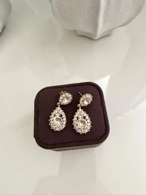 Rosé droppformade örhängen med stenar - Snygga örhängen i rosé med droppformad design. Örhängena är dekorerade med gnistrande klara stenar och små pärlliknande detaljer runt kanterna🫶🏼