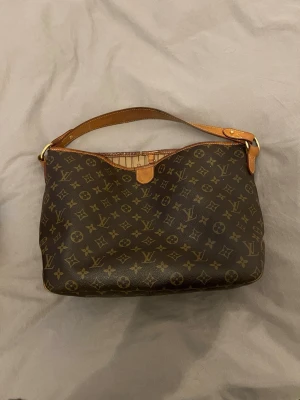 Louis Vuitton Monogram axelremsväska - Snygg handväska från Louis Vuitton i klassiskt brunt monogrammönster med LV-loggor.  Väskan är köpt från A retro tale där äktenheten också intygats, beställnings bekräftelse samt dustbag från de medföljer.