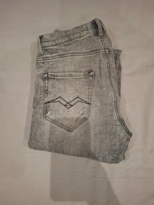 Replay anbass - Snygga grå skinny jeans med slitningar på knäna och coola detaljer på bakfickan. Jeansen har en tvättad look och klassisk femficksdesign. Perfekta för en trendig streetstyle.