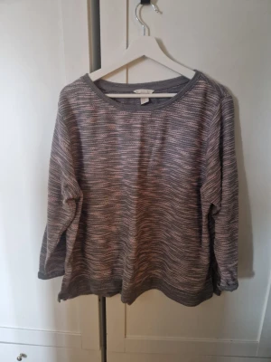 Gråmelerad tröja från H&M - Säljer en gråmelerad långärmad tröja från H&M. Tröjan har en avslappnad passform, rund halsringning och ett diskret randigt mönster i olika grå nyanser. Perfekt för en chill och stilren look.