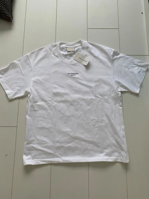 Vit t-shirt från Drôle de Monsieur - Säljer en clean vit t-shirt från Drôle de Monsieur med trycket 'NOT FROM PARIS MADAME' i svart på bröstet. Klassisk passform och rund halsringning. Perfekt basic med en twist för dig som gillar stilrena plagg med statement.