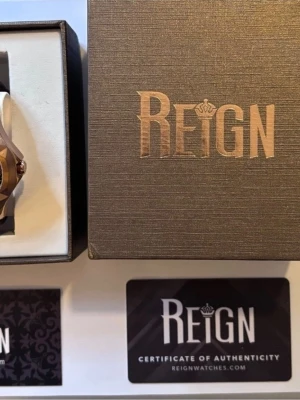 Reign Dantes Automatic Skeleton Dial Men's Watch REIRN4701 - Snygg klocka från Reign med brunt läderband och urtavla i svart och guld. Klockan har synlig mekanik och romerska siffror på urtavlan. Kommer i originalask med certifikat. Jeweled Automatic Miyota 8N24 Movement Jewel Bearings: 20 Jewels 36-Hour Power Reserve Beats per Hour (BPH): 21600/Hour Sapphire-Coated Mineral Crystal Skeleton Dial Observation Caseback to view Movement Logo-Engraved Crown Crown Protector Case Design 316L Surgical-Quality Stainless. 47mm Diameter 5 ATM Water Resistance