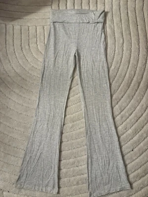 Grå bootcut leggings - Säljer ett par ljusgrå leggings med bootcut. De är mjuka och stretchiga, perfekta för en avslappnad look. Materialet känns som bomullsmix och de har en enkel, stilren design utan synliga loggor eller detaljer.