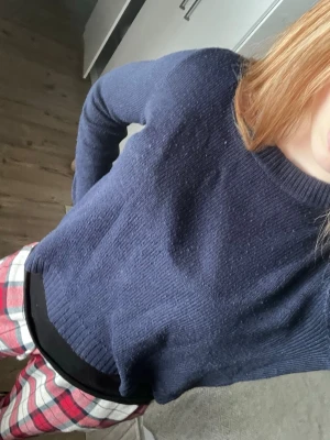 Mörkblå stickad tröja med rund hals - Mysig mörkblå stickad tröja med rund halsringning och ribbstickade muddar vid ärmslut och nederkant. Perfekt för lager-på-lager och enkel att matcha med olika outfits.