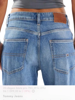 Blå wide leg jeans från Tommy Jeans - Snygga blå jeans med wide leg-modell från Tommy Jeans. Jeansen har hög midja, klassiska fem fickor och en liten logga på bakfickan. Tillverkade i denim med en ljus tvätt och raka, vida ben för en avslappnad look. Oanvända, strl W:27 L:32