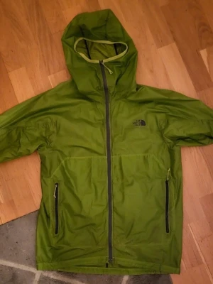 Grön vindjacka från The North Face - Snygg grön vindjacka från The North Face. Jättefin har ett pytte hål och pyttefläck som inye märks av se markeringar 