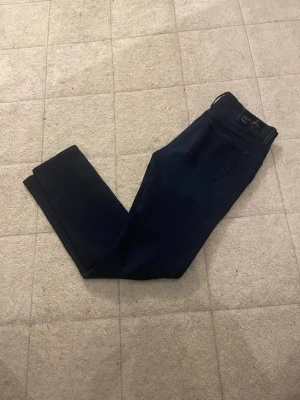 Mörkblå jeans från Jacob Cohen - Snygga mörkblå jeans från Jacob Cohen med klassisk femficksmodell och diskret logga på bakfickan. Jeansen har smal passform och är tillverkade i mjukt denimtyg som ger en skön känsla. Perfekta för dig som gillar stilrena och tidlösa plagg.