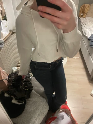 Vit cropped hoodie med huva - Säljer en vit cropped hoodie med huva. Hoodien har långa ärmar och en avslappnad passform. Materialet känns mjukt och bekvämt. Den är från new yorker i storlek XXS och är aldrig använd. 