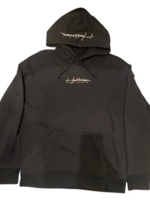 Svart hoodie från Hollister - Svart hoodie från Hollister med broderad logga på bröstet och huvan. Klassisk känguruficka framtill, snörning i huvan och lång ärm. Perfekt för en chill och avslappnad stil.