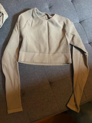 Beige ribbad croppad långärmad topp från AIMN - Trendig beige croppad topp med långa ärmar och ribbad struktur. Perfekt för att styla med höga jeans eller kjol. Enkel och stilren design som passar till många outfits.