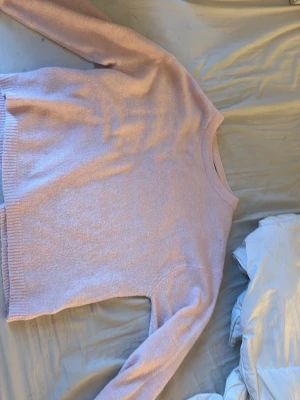 Ljusrosa stickad tröja - Mysig ljusrosa stickad tröja med rund halsringning och ribbade muddar vid ärmslut och nederkant. Perfekt för lager på lager och enkel att matcha med jeans eller kjol. Tröjan har en avslappnad passform och är tillverkad i mjukt material.