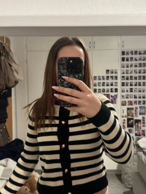  H&M kofta - Snygg ribbstickad kofta från H&M i svart och kräm vit. Tröjan har super fina och eleganta guldknappar som livar upp outfiten! Koftan är k storlek xs och aldrig använd!💕