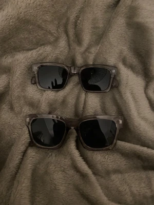 Svarta solglasögon med transparent båge - Snygga solglasögon med svarttonade glas och transparent grå båge. Klassisk rektangulär form som passar till de flesta stilar. Perfekta för soliga dagar och ger en cool vibe till din outfit.